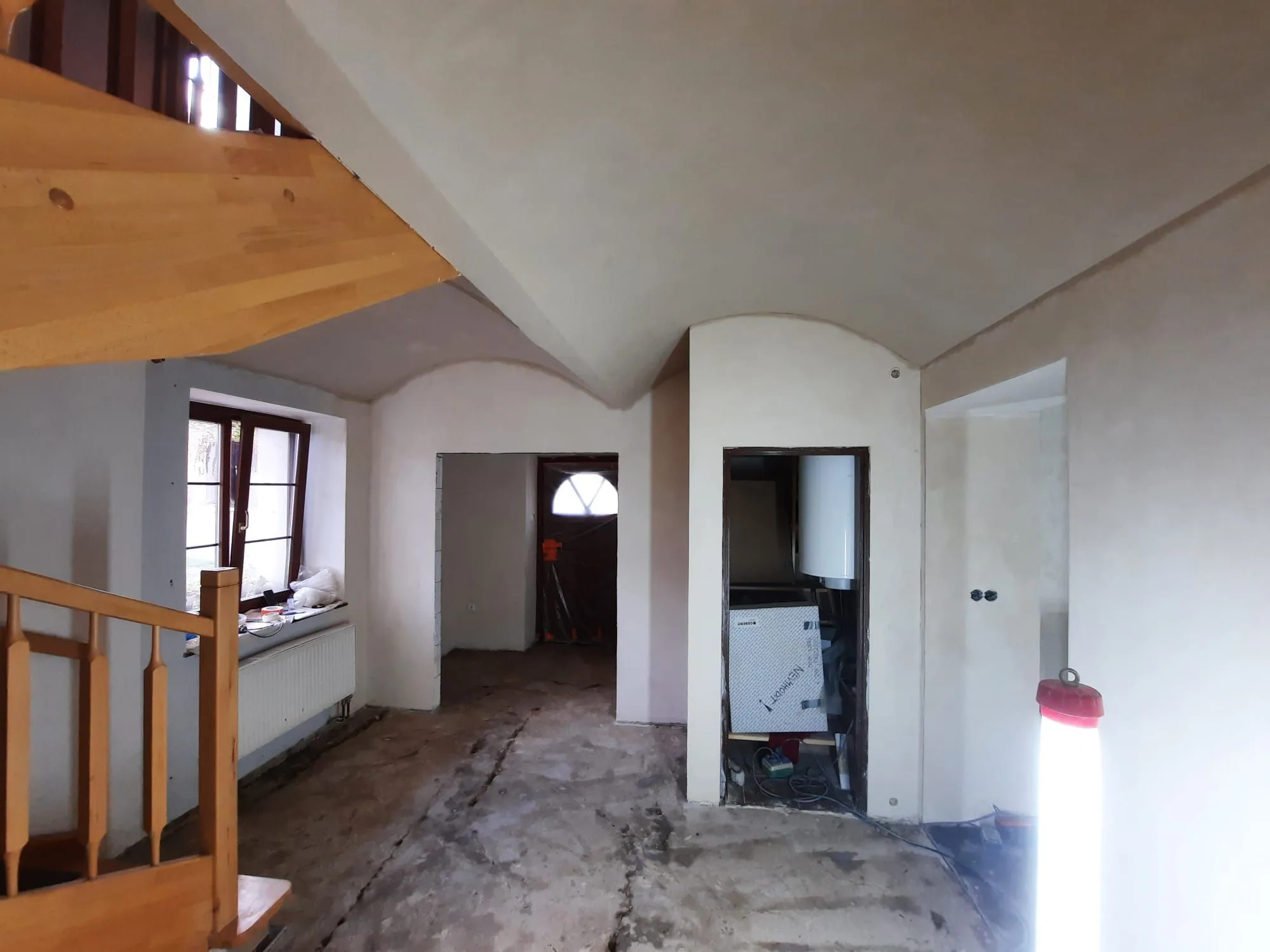 Omítnuté stěny a&nbsp;dřevěné schodiště, během prací