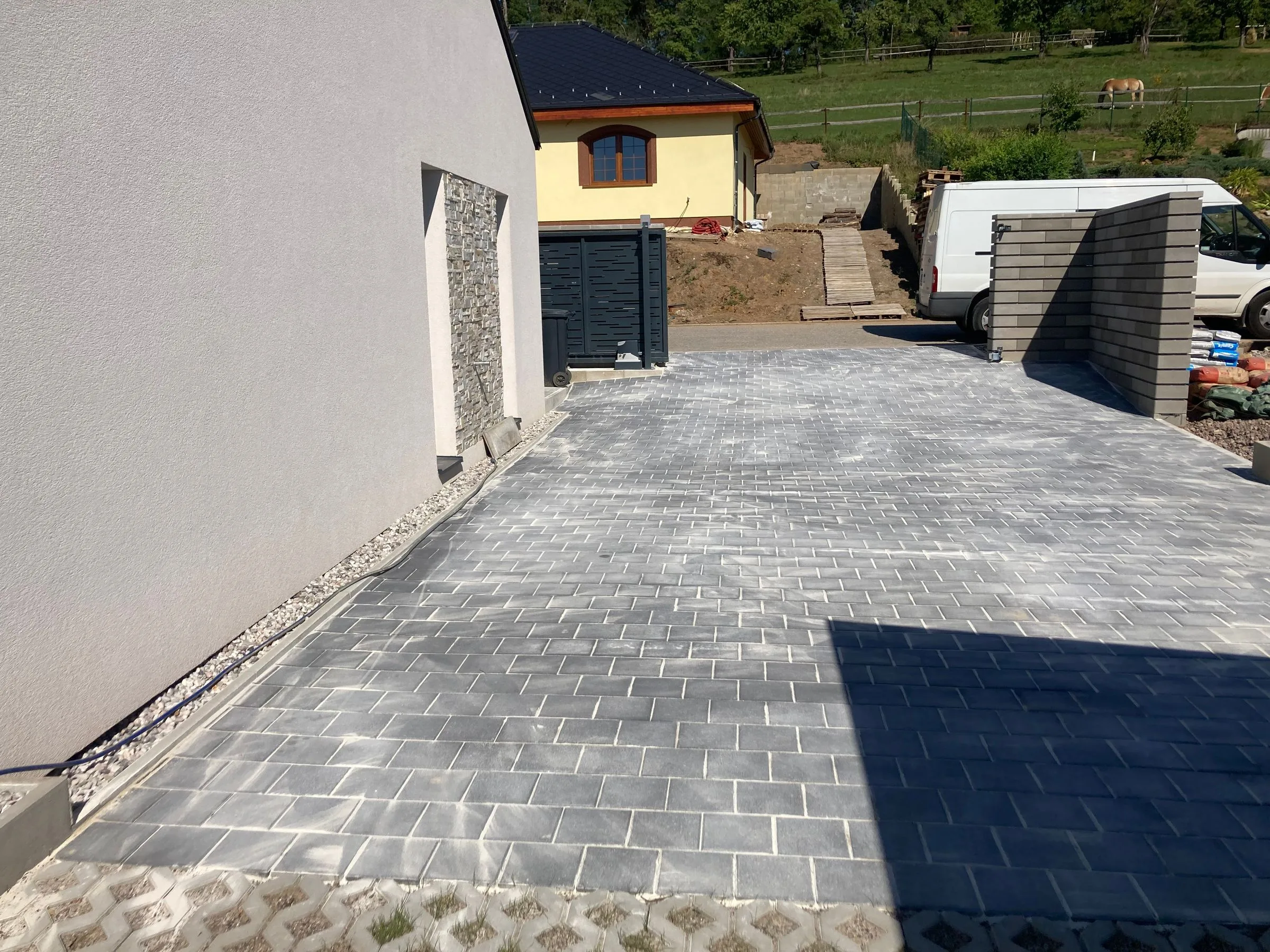 Příjezd ze šedé zámkové dlažby k&nbsp;domu