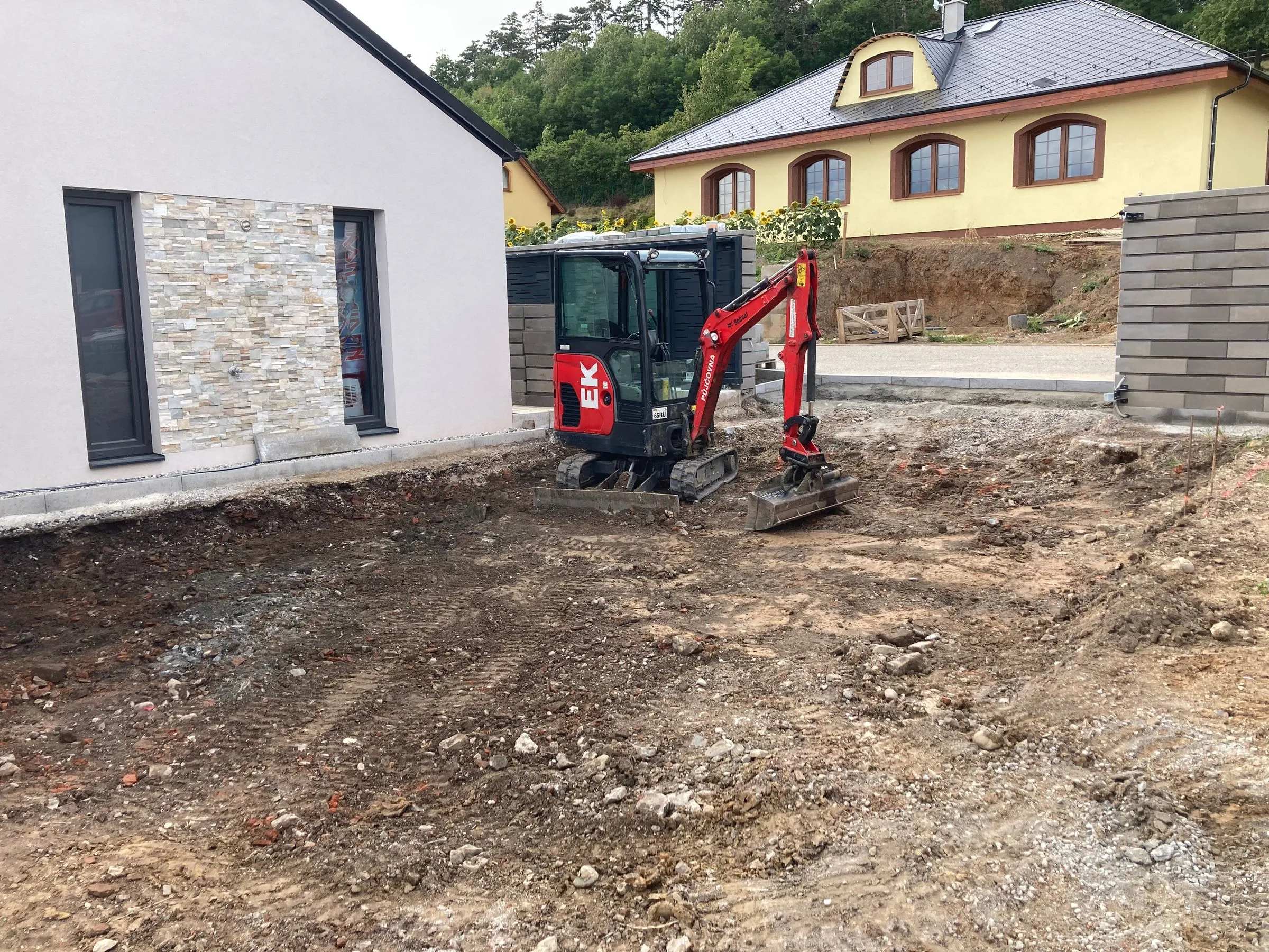 Odkopaná plocha budoucího příjezdu před domem a&nbsp;minibagr