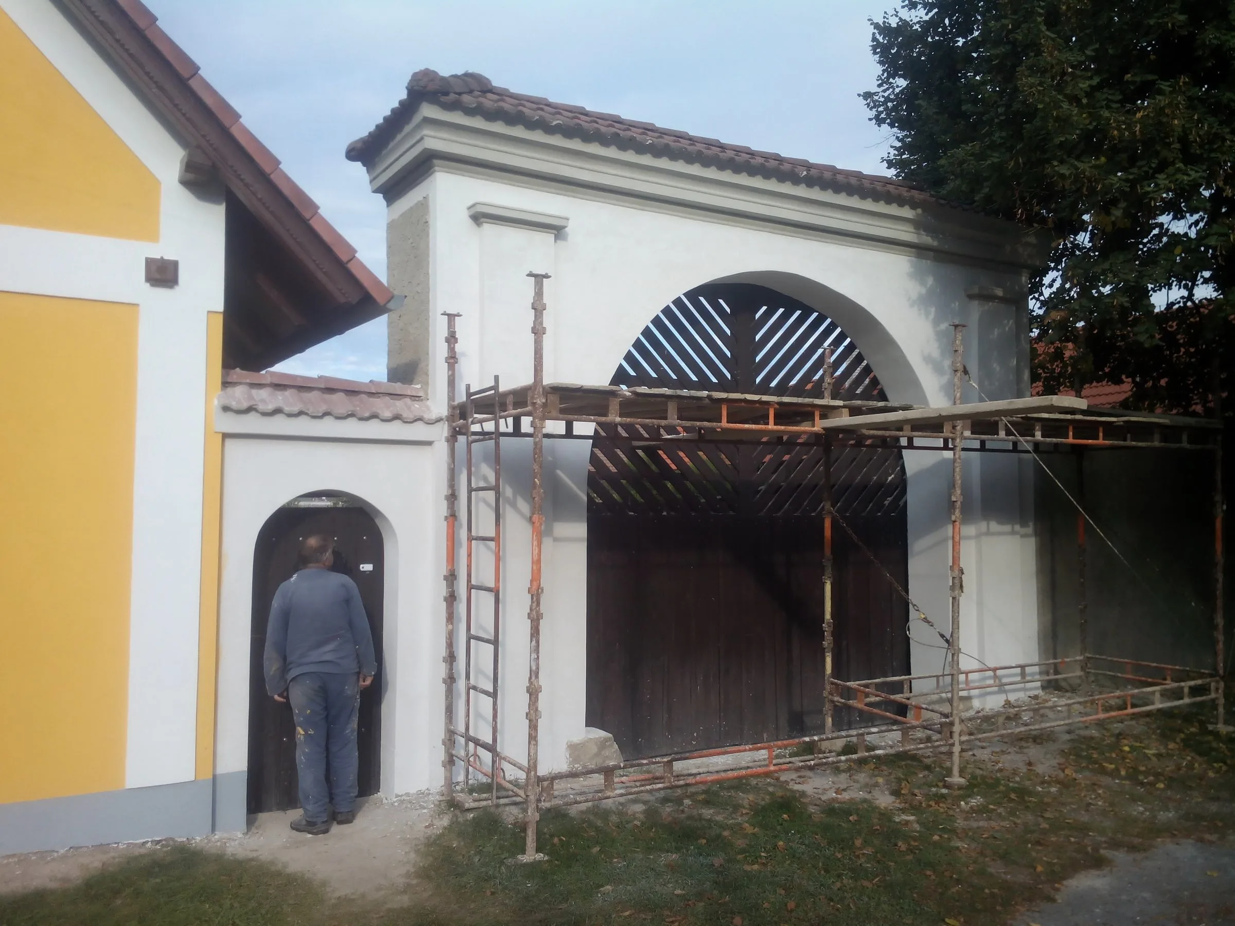Vjezdová brána v&nbsp;lešení, štuky a&nbsp;omítka před konečným nátěrem