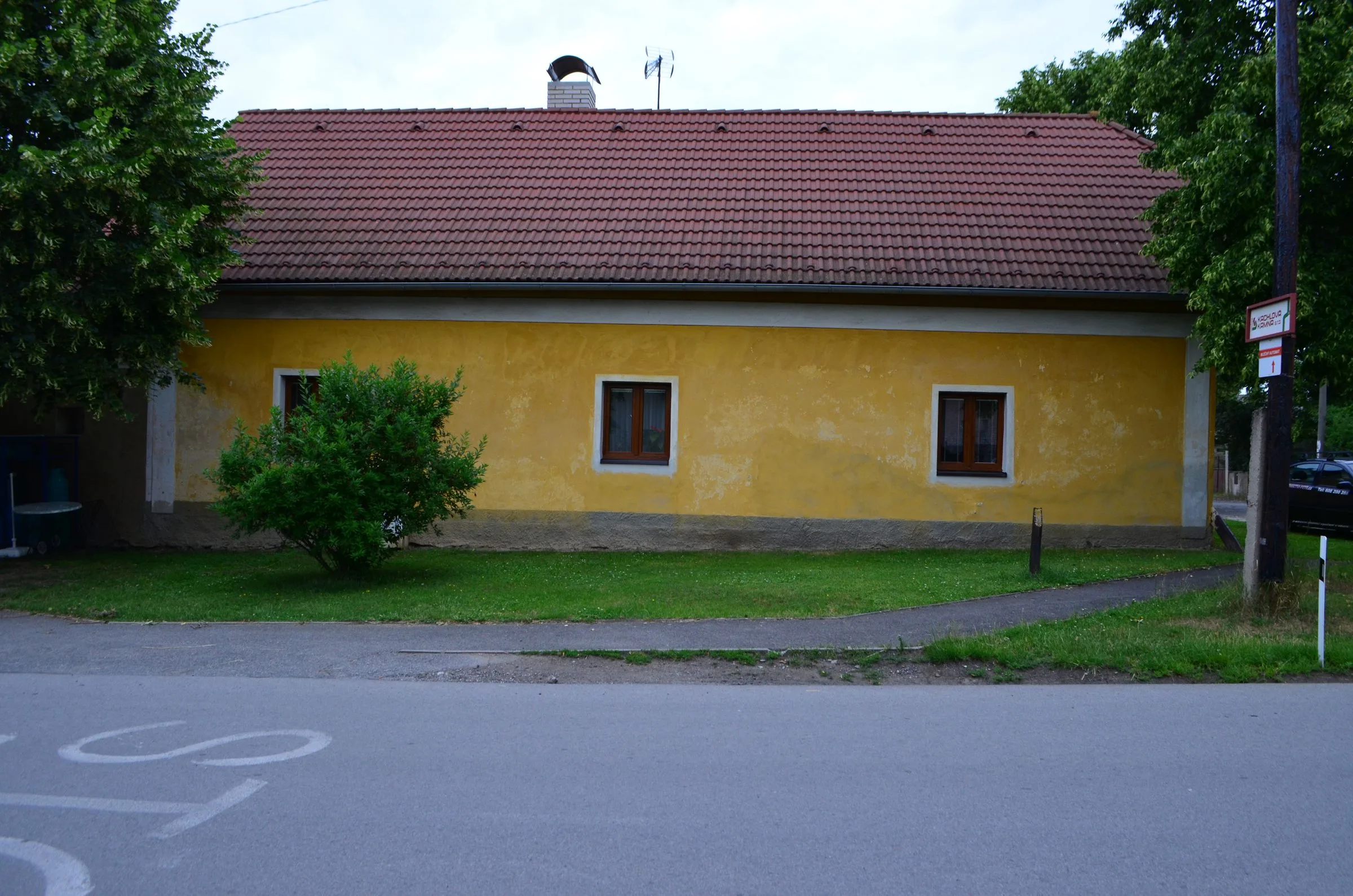 Dům od silnice se starou vybledlou fasádou